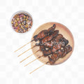 Skewered meat on a plate with a small bowl of sauce on a white background