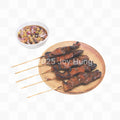 Skewered meat on a wooden plate with a small bowl of sauce on a white background