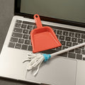 Laptop with a red dustpan and white duster on top